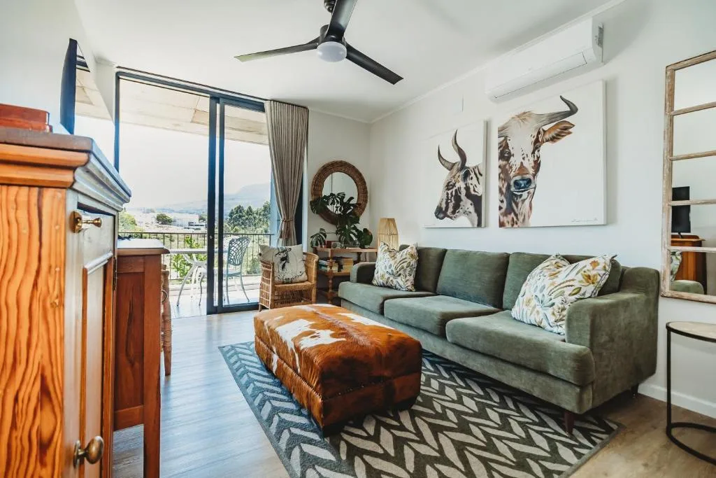 Bright living room with green sofa, animal artwork, and mountain views through glass doors