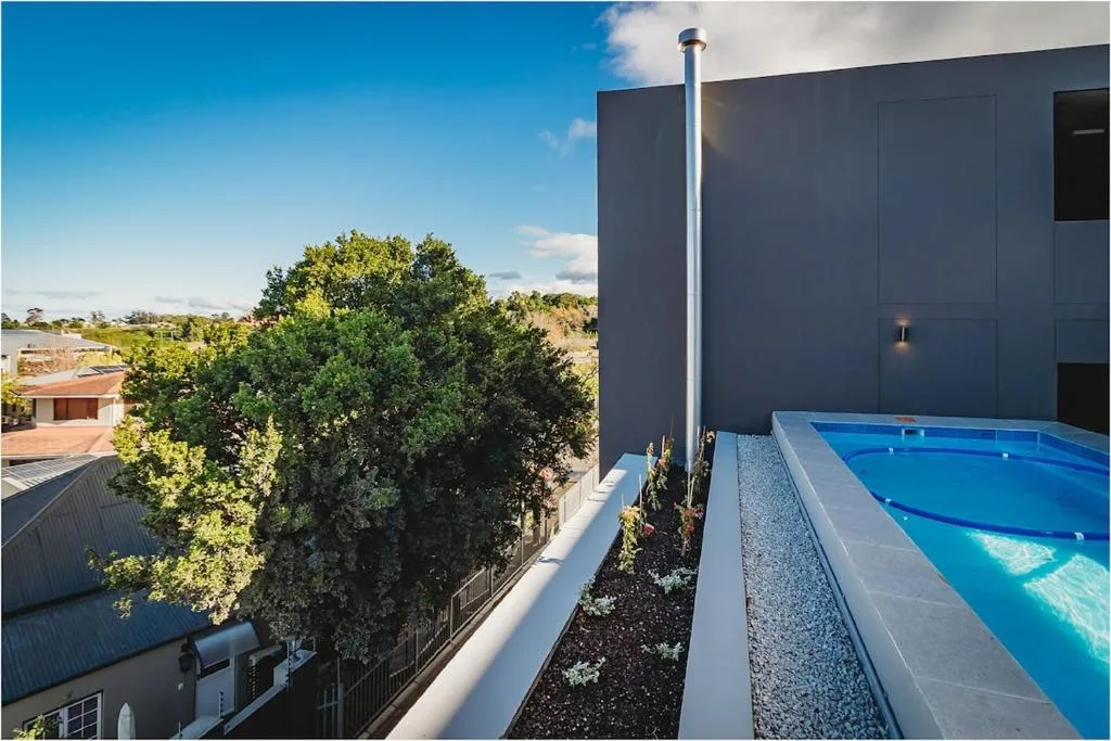 Bright blue swimming pool beside modern dark building with mountain views