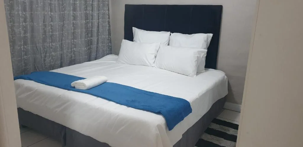 Modern bedroom with neatly made bed, blue runner, and white pillows