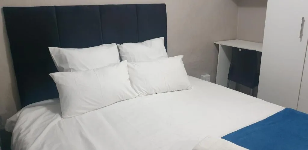 Modern bedroom with dark headboard, white pillows and bedding, side table