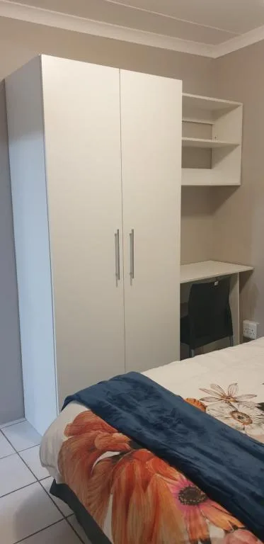 Bedroom with bed, white wardrobe, and built-in shelving storage