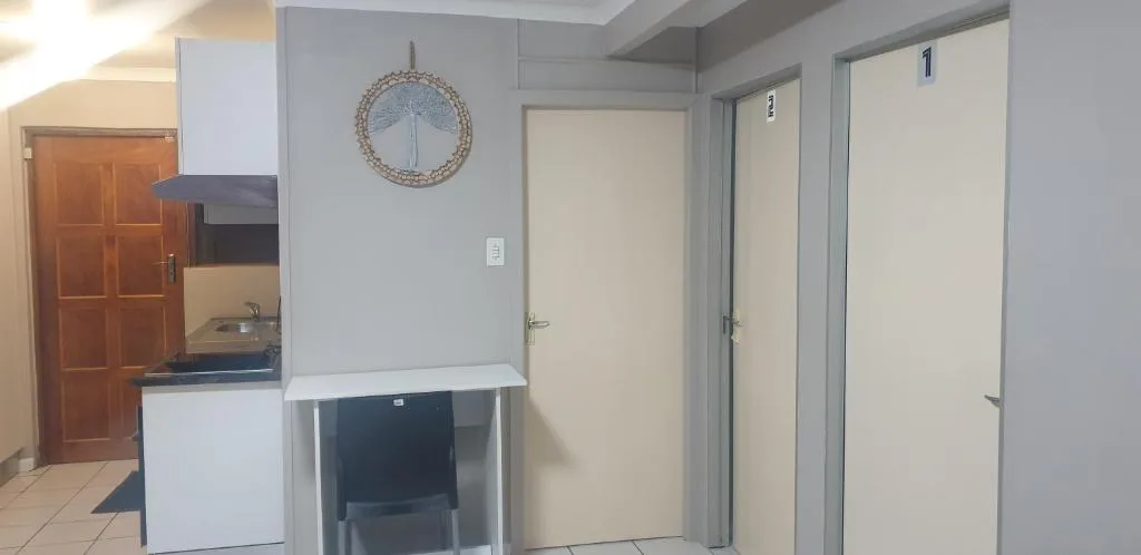 Interior hallway with kitchen area, decorative clock, and bedroom doors