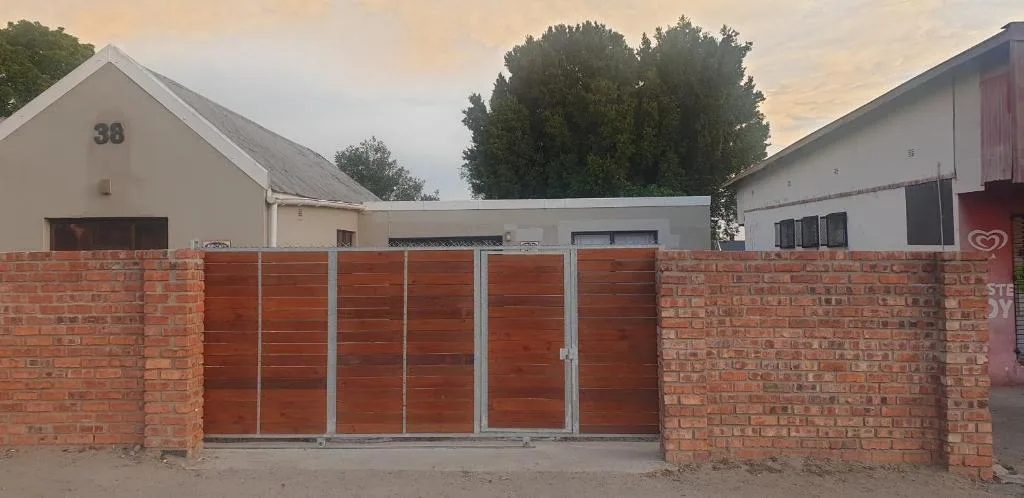 Front entrance with red metal gates and brick boundary wall