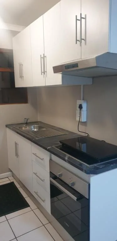 Modern kitchen with white cabinetry, black countertop, and built-in oven