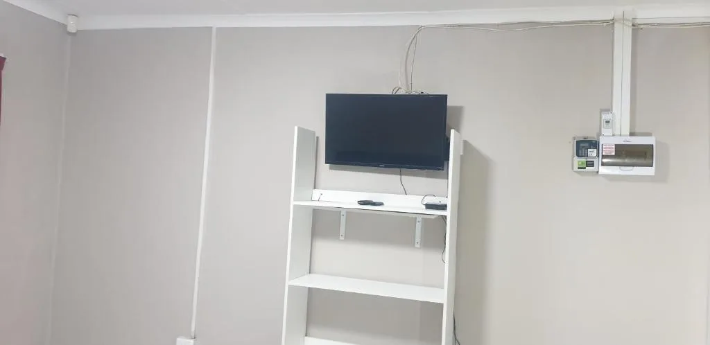 Wall-mounted TV above white shelving unit in bright lounge area