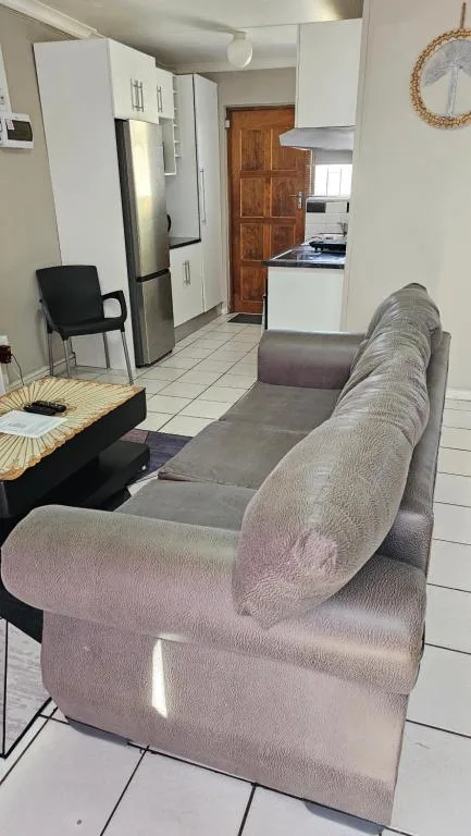 Open-plan lounge with gray sofa, kitchen visible in background