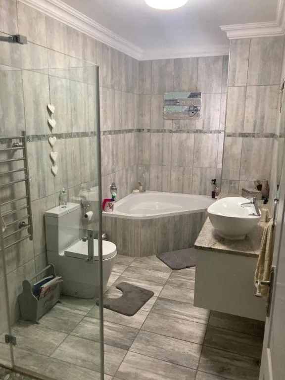 Modern bathroom with corner bath, separate shower enclosure, and vanity sink