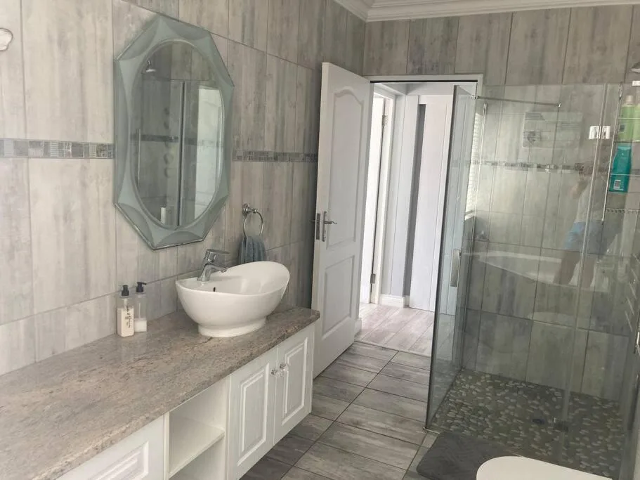 Modern bathroom with vessel sink, large mirror, and walk-in shower enclosure