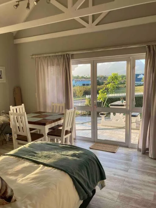 Spacious bedroom with bed, dining table, and glass doors overlooking water view