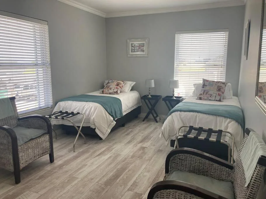 Bright twin bedroom with white shuttered windows and neutral décor