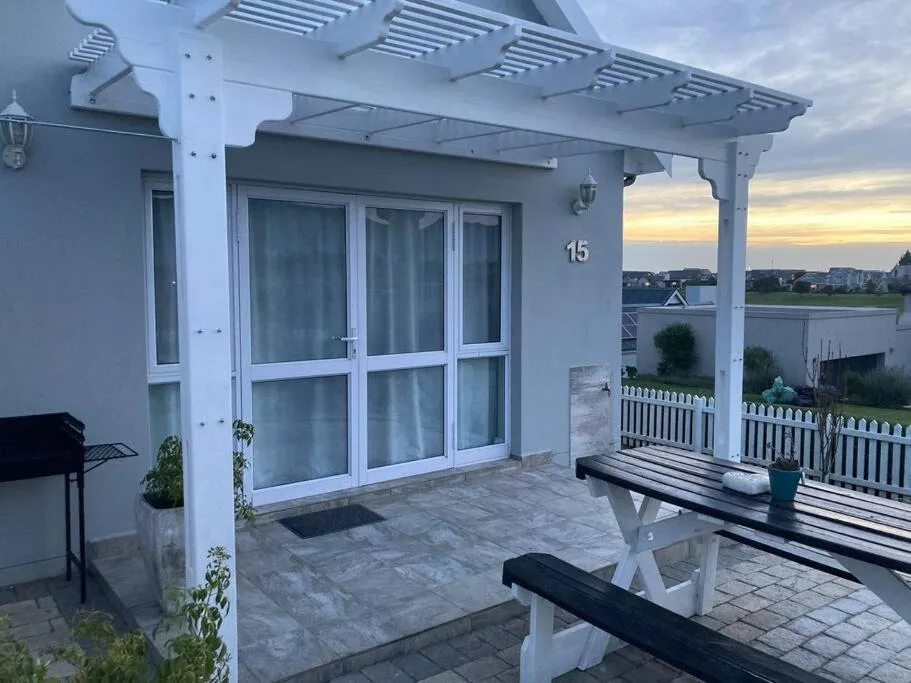 Modern patio with pergola, outdoor seating, and lagoon views at sunset