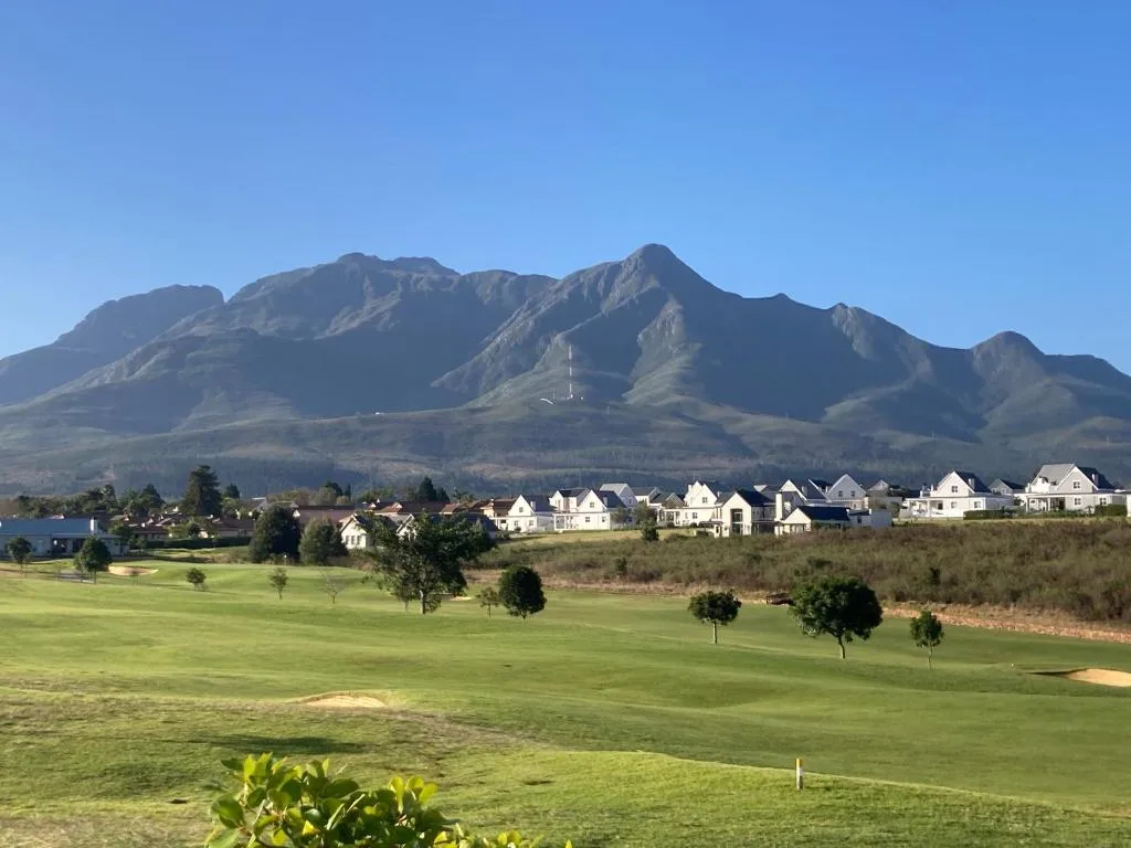 Dramatic mountain backdrop overlooking manicured golf course and white estate homes