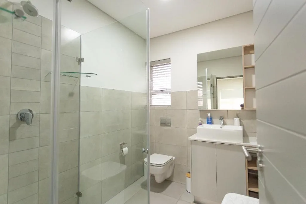 Modern bathroom with walk-in shower, white vanity, and toilet
