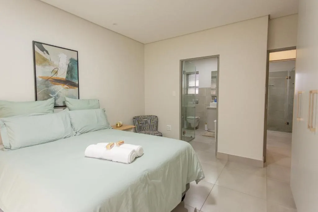 Light-filled bedroom with queen bed, ensuite bathroom, and modern decor