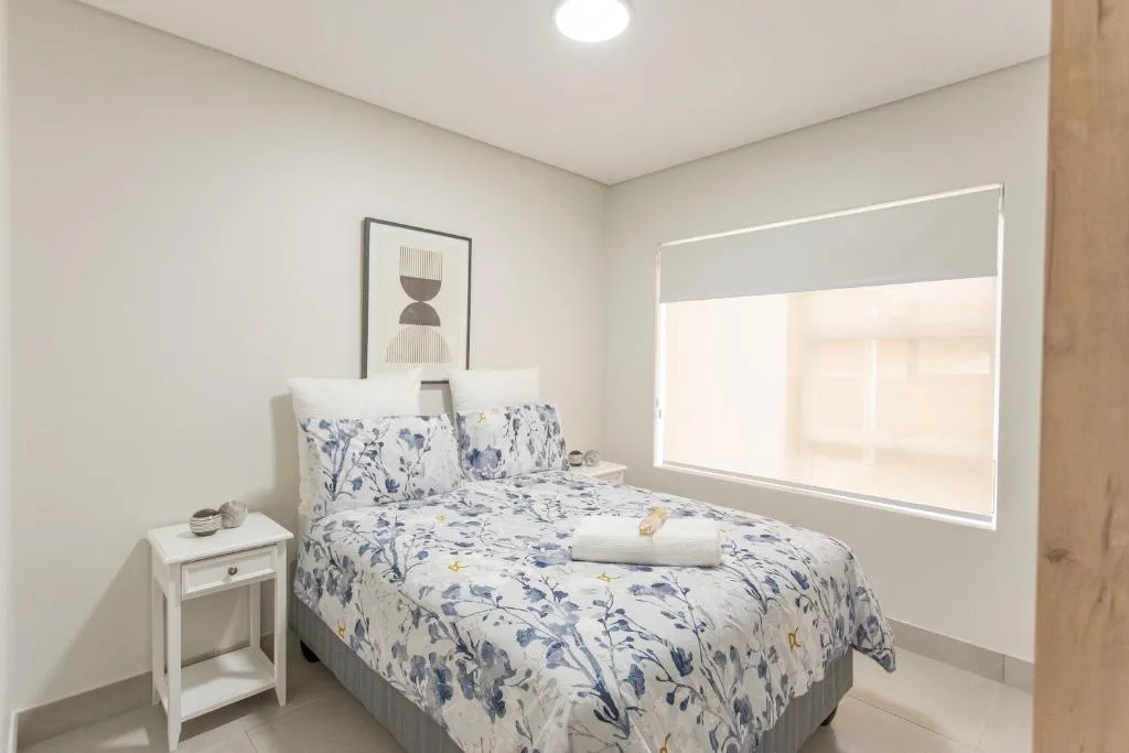 Bright bedroom with floral patterned bedding and white nightstand