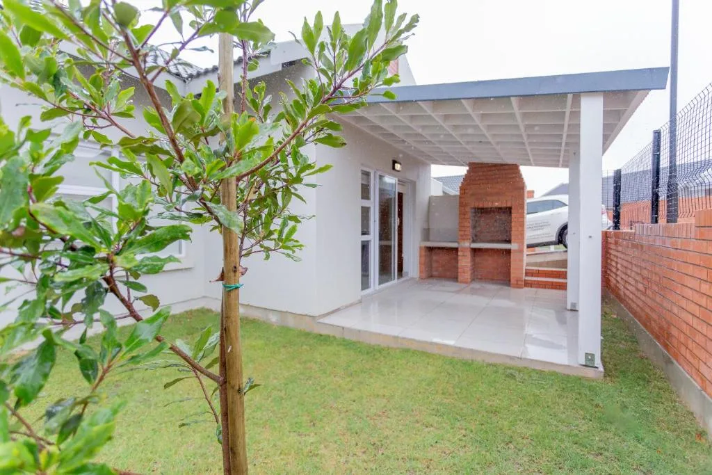 Modern patio with pergola, brick fireplace, and manicured lawn