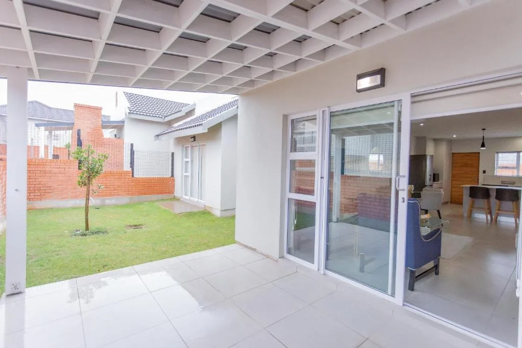 Modern patio with tiled flooring overlooking manicured lawn and garden area