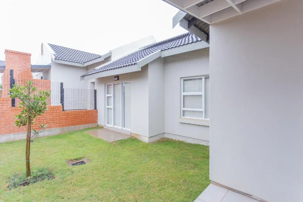 Modern white house with blue tile roof and manicured garden lawn