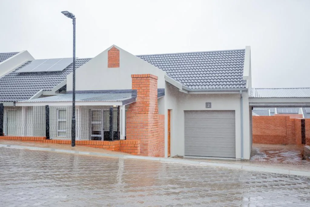 Modern white house with red brick chimney and gray garage door