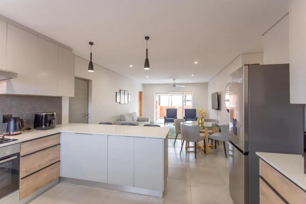 Modern open-plan kitchen with white cabinetry and island bench overlooking lounge area