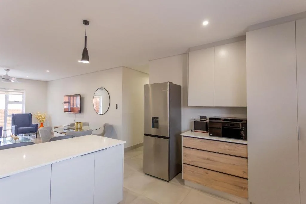 Modern kitchen with stainless steel fridge, white cabinetry, and island counter