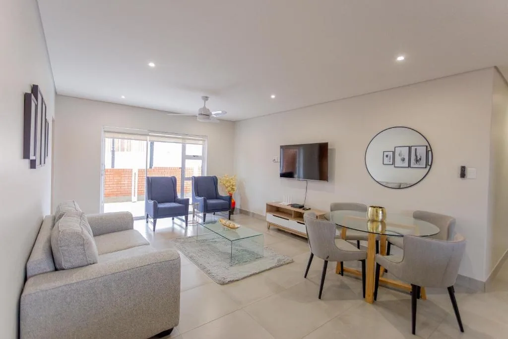 Modern lounge with comfortable seating, dining table, and wall-mounted television