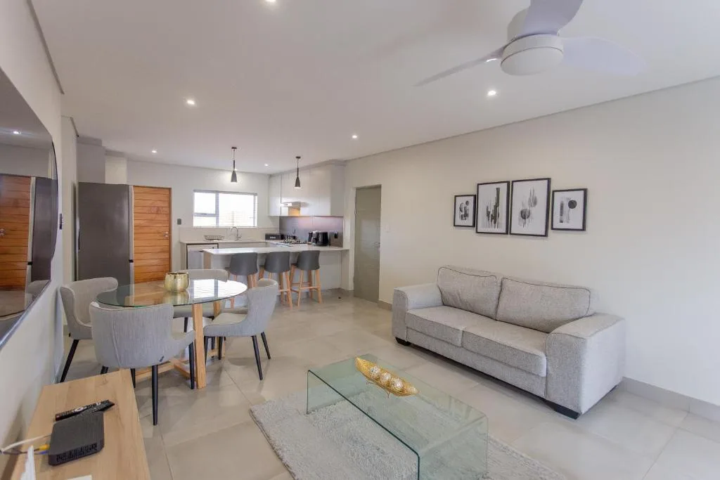 Modern lounge with beige sofa, glass coffee table, and framed wall art