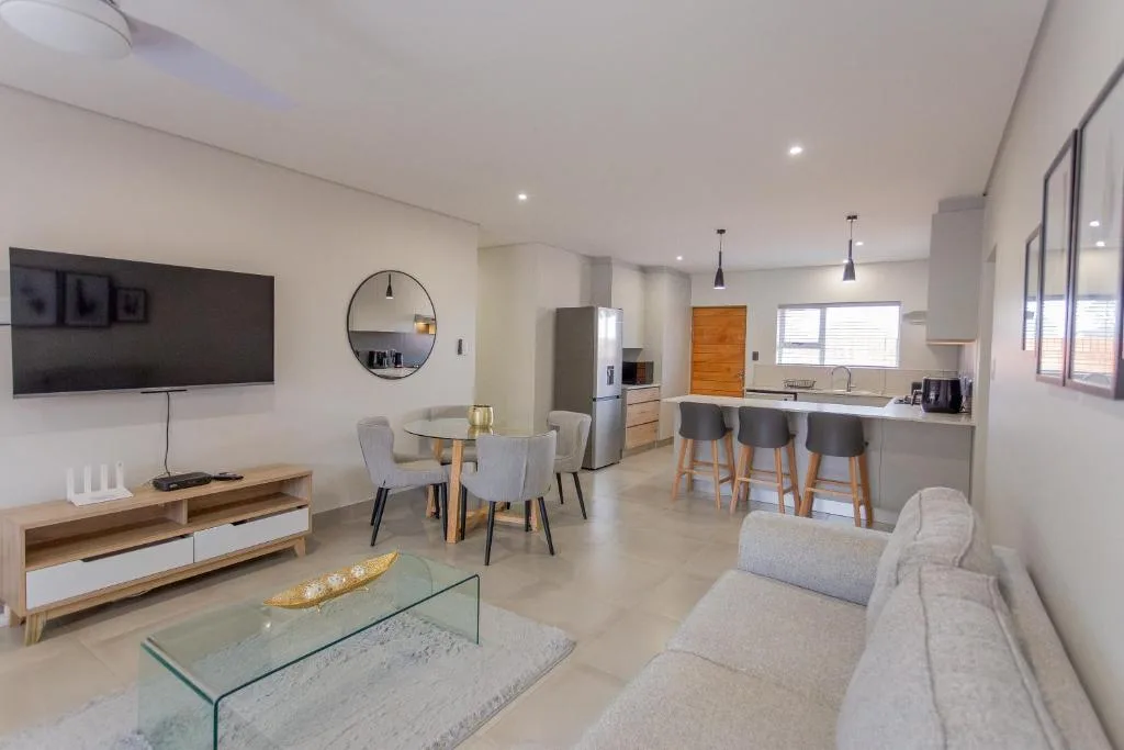 Modern open-plan lounge with TV, sofa, and dining area visible