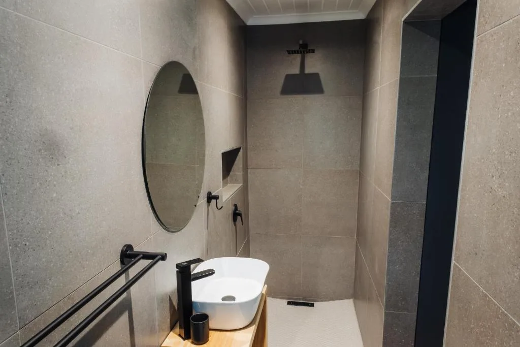Modern bathroom with round mirror, white sink, and rainfall shower head