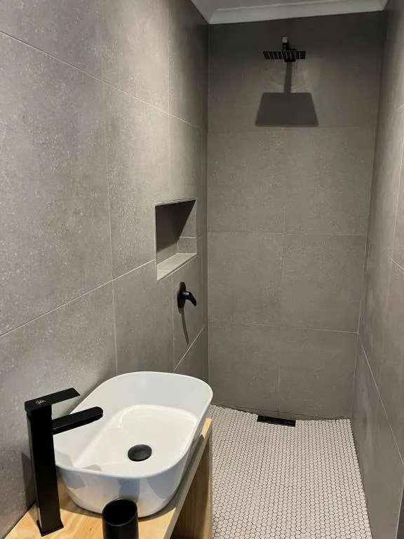 Modern bathroom with rainfall showerhead, white sink, and tiled walls