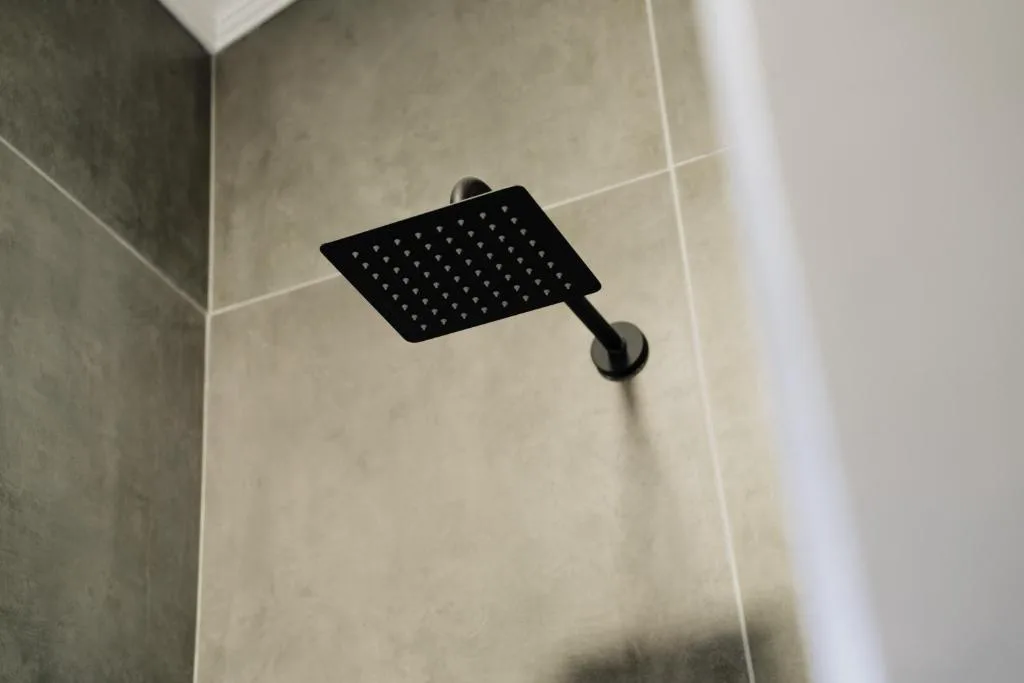 Modern black rainfall showerhead mounted on tiled bathroom wall