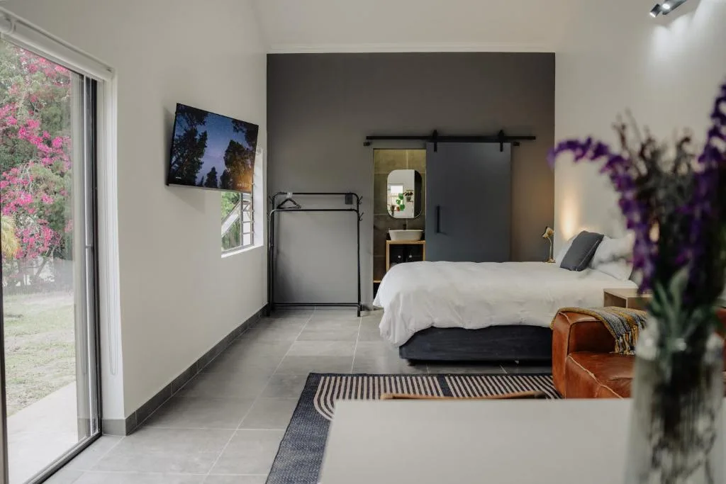 Modern bedroom with white bedding, sliding barn door, and garden views