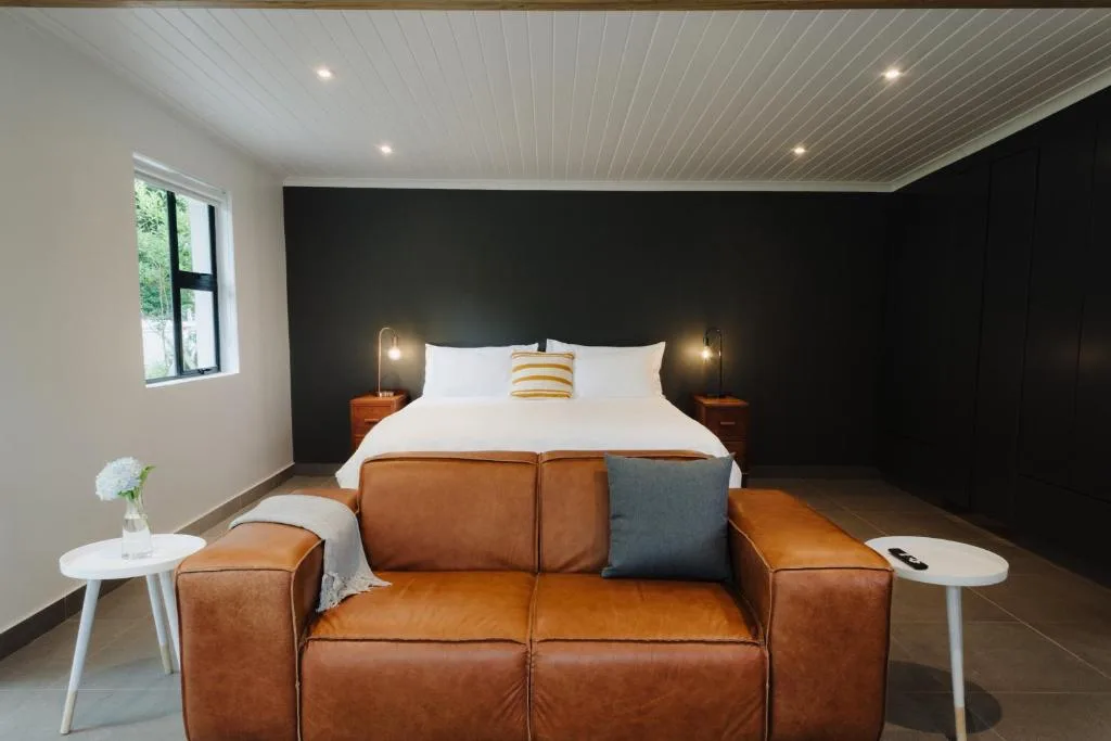 Modern bedroom with black accent wall, white ceiling, and leather seating area