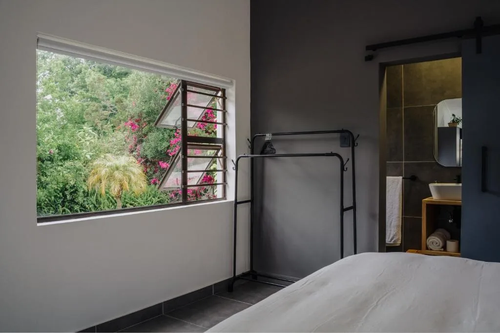 Modern bedroom with black metal bed frame and garden view through window