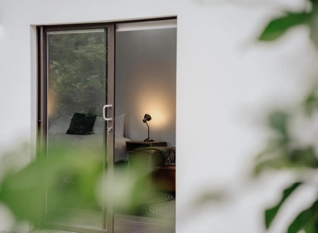Bedroom interior with bedside lamp and garden view through glass doors