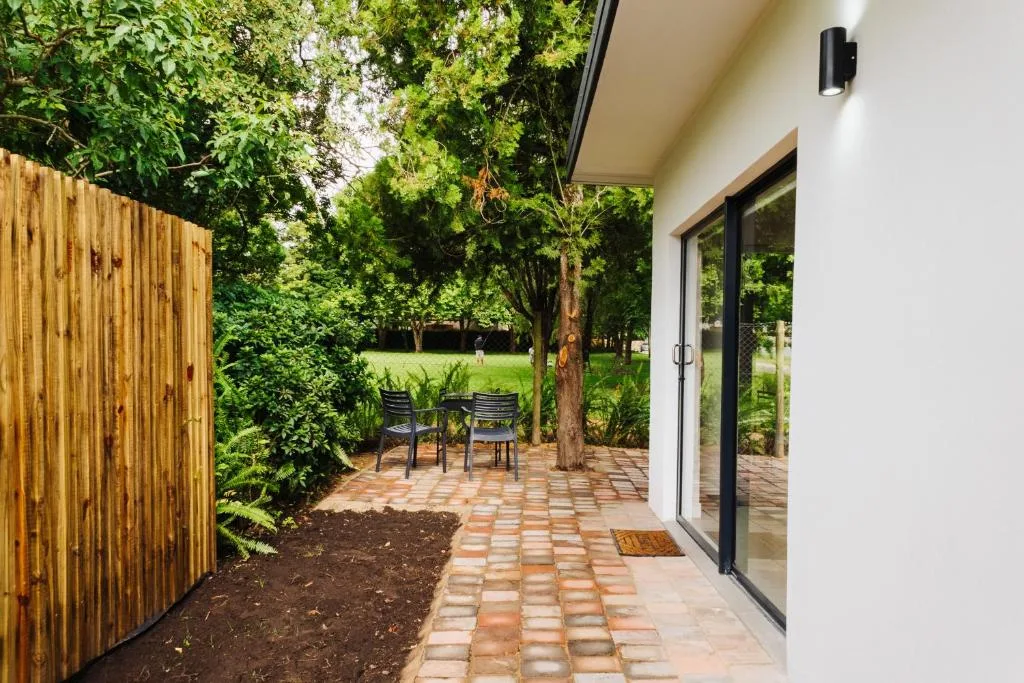 Paved patio area with seating chairs surrounded by lush green trees