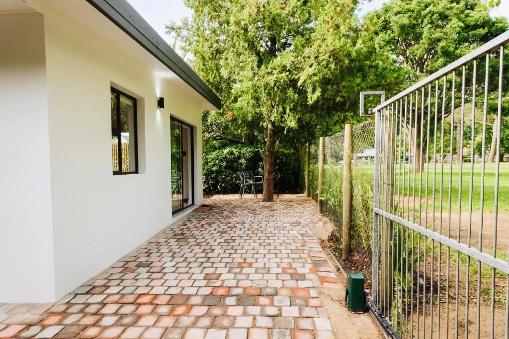 Brick paved patio with white building and mature trees surrounding