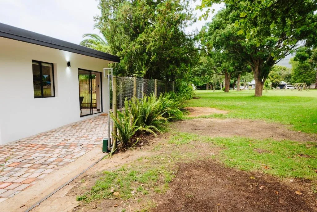 Modern white cottage with brick patio entrance and manicured garden surroundings