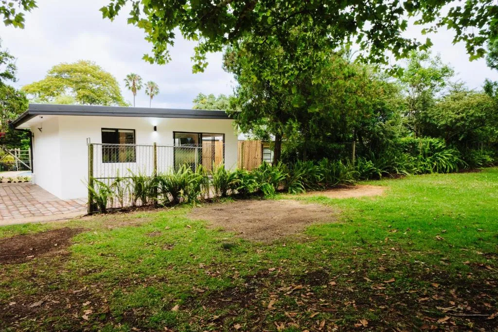 Modern white cottage with deck and manicured gardens on expansive lawn