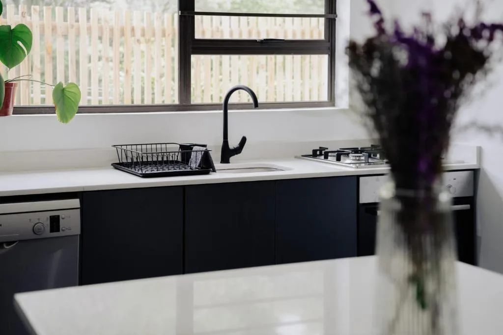 Modern kitchen with black cabinetry, white countertop, and window view
