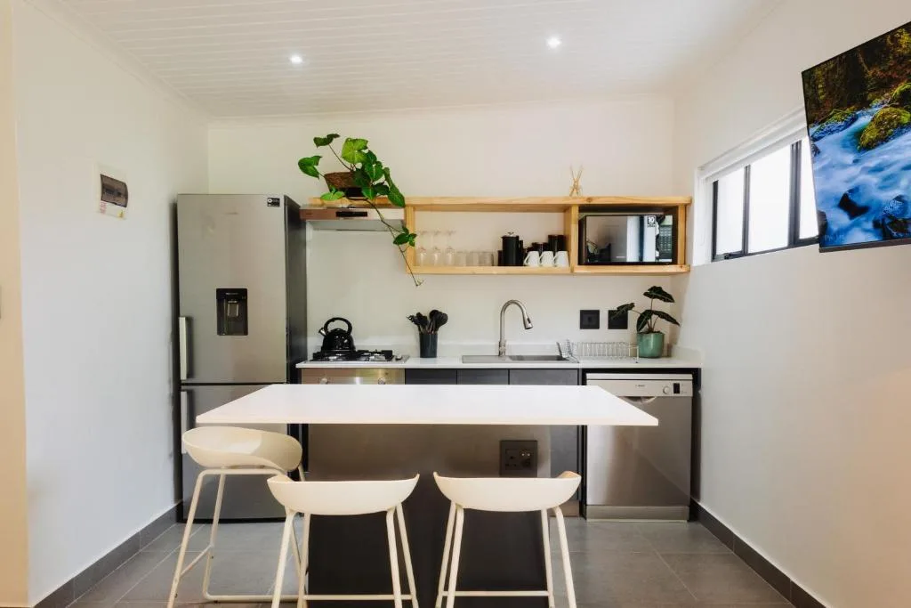 Modern kitchen with stainless steel appliances, wooden shelving, and dining counter