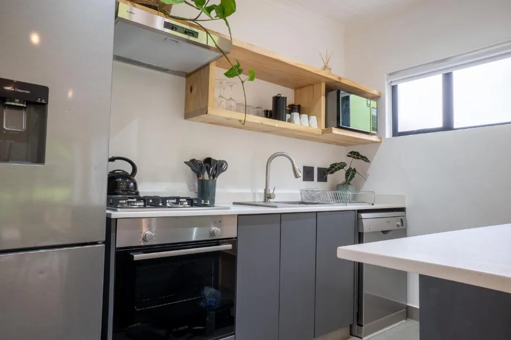 Modern kitchen with gas stove, sink, dark cabinetry, and wooden shelving