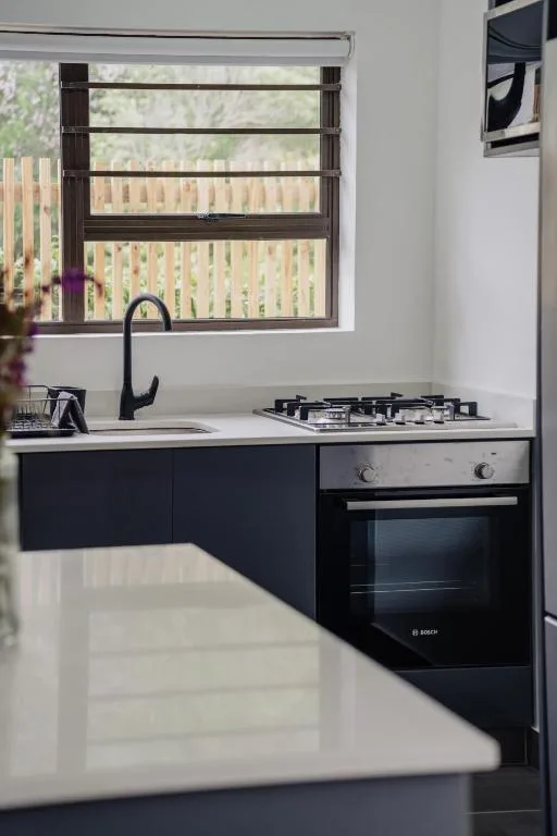 Modern kitchen with gas cooktop, sink, and black cabinetry under window