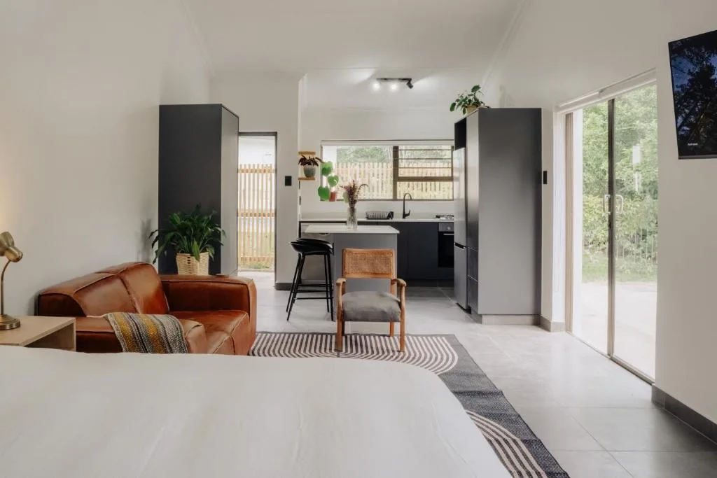 Modern lounge with cognac leather sofa overlooking open-plan kitchen and deck access