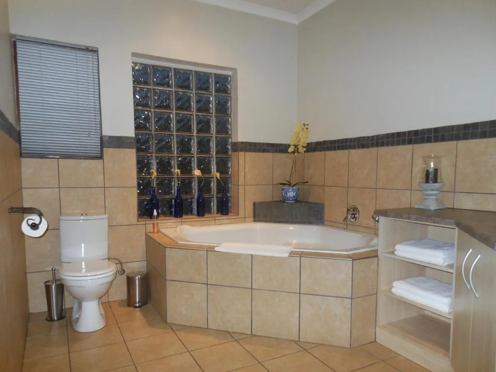 Spacious bathroom with large soaking tub, toilet, and decorative glass block window
