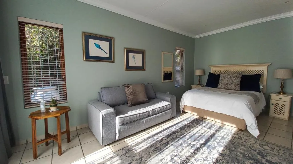 Bedroom with bed, sofa, mint walls, and natural light from window