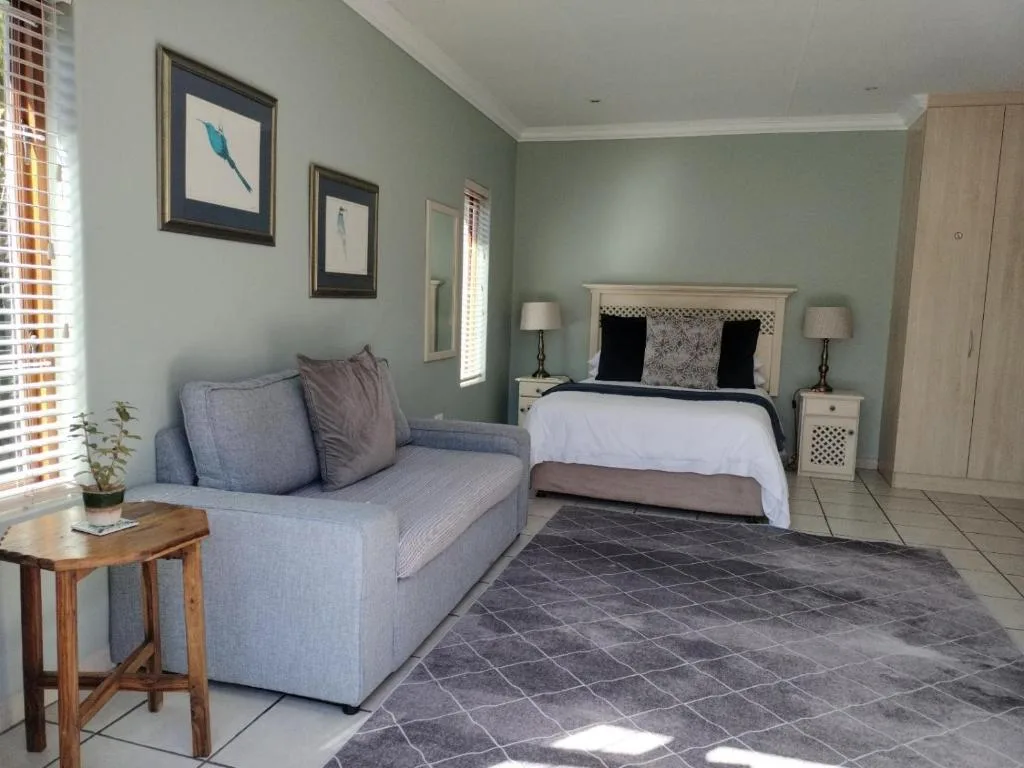 Bright bedroom with queen bed, lounge seating, and bird artwork