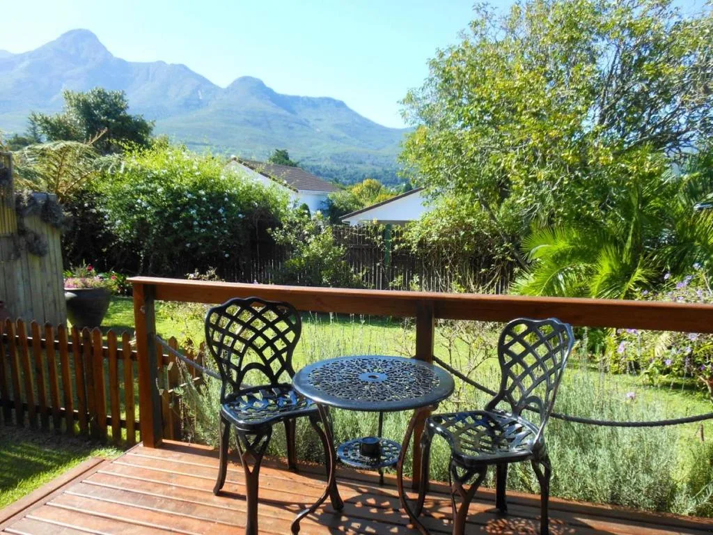 Wooden deck with seating overlooking lush garden and distant mountains