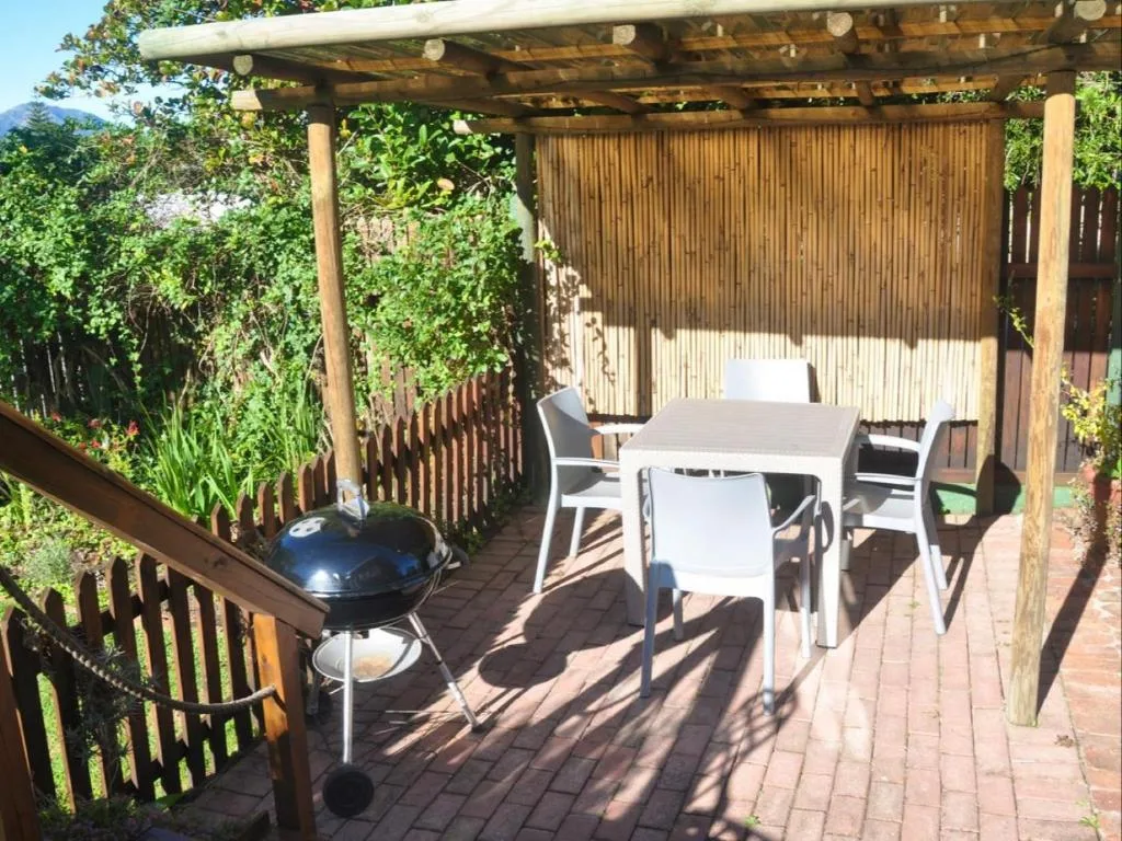 Shaded patio with dining table, chairs, and braai grill