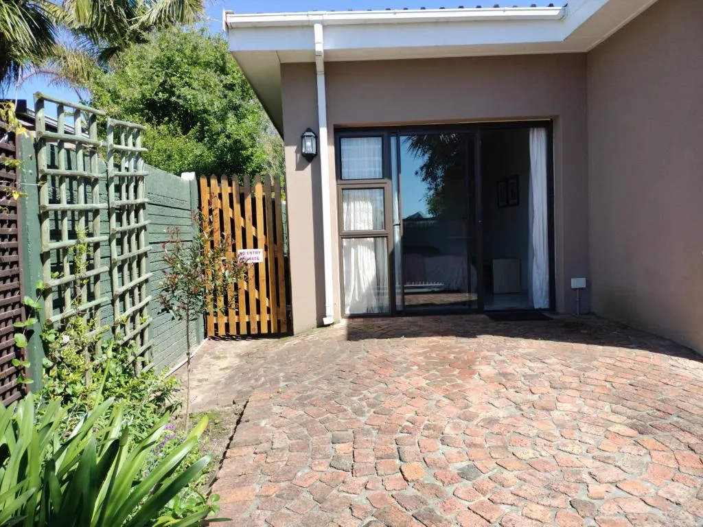 Modern home entrance with brick paving, yellow gate, and manicured gardens